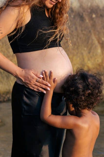 Young child touching mother pregnant belly